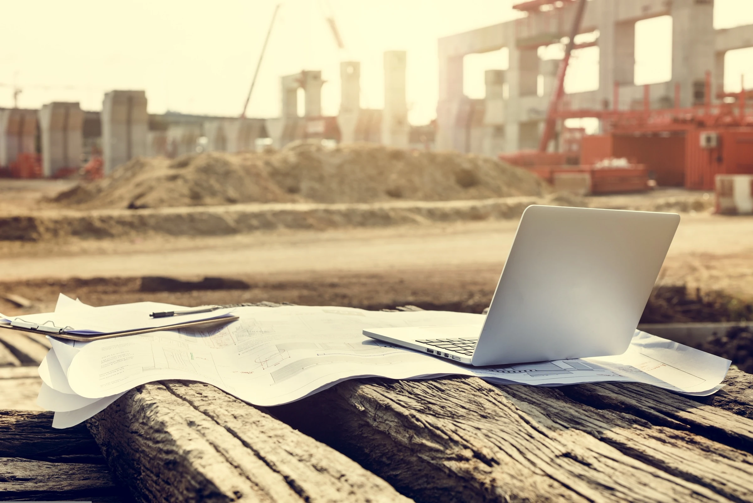 Ordinateur portable et plans posés sur un chantier
