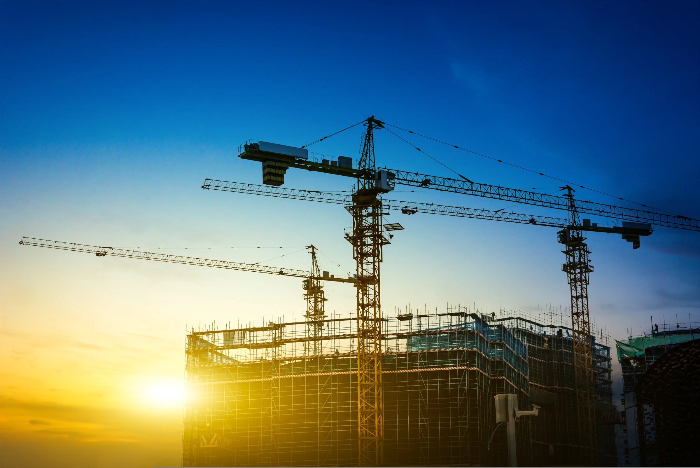 Chantier de construction : grues à tour au-dessus d'un immeuble, au coucher du soleil